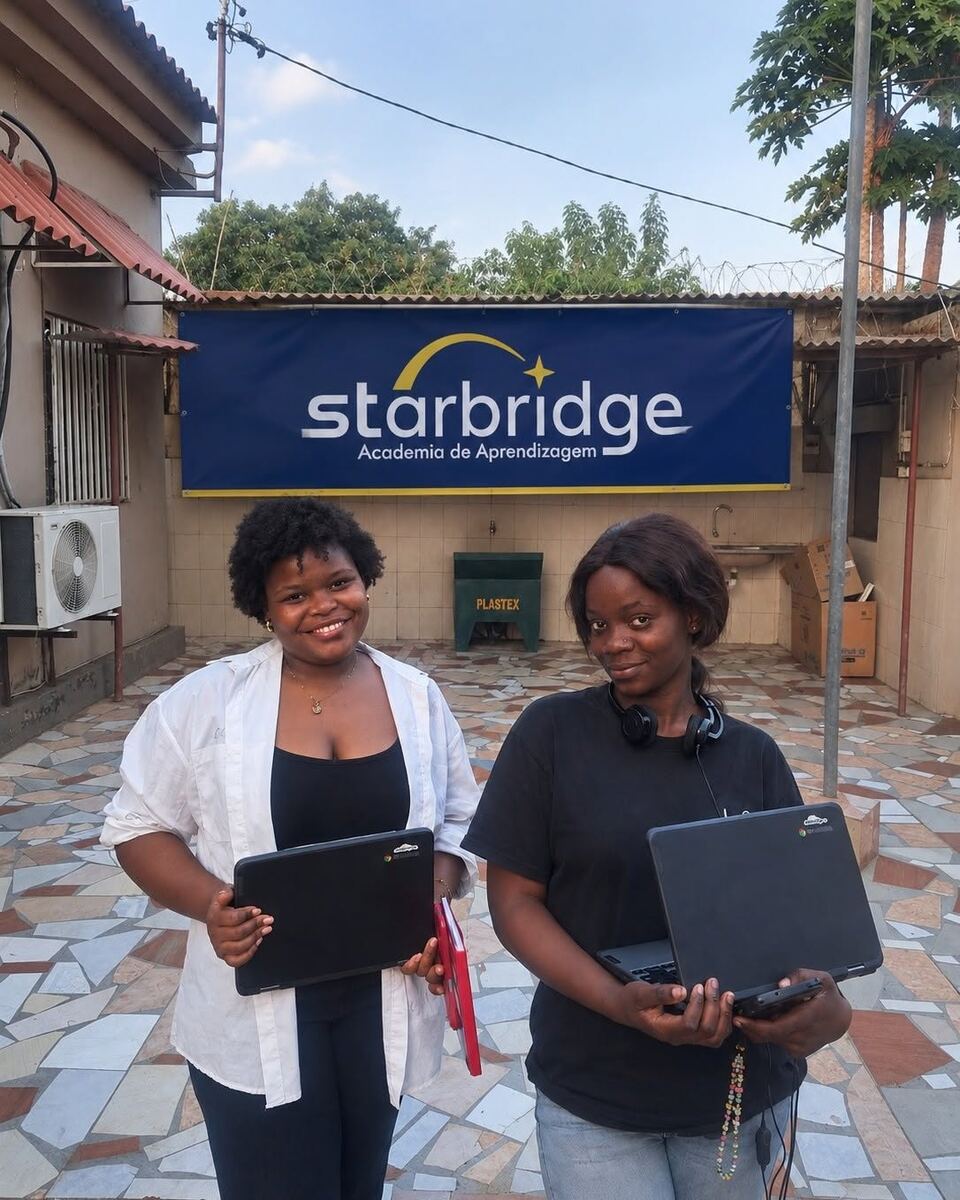 Two students holding Chromebooks outside the academy beneath its Starbridge sign.
